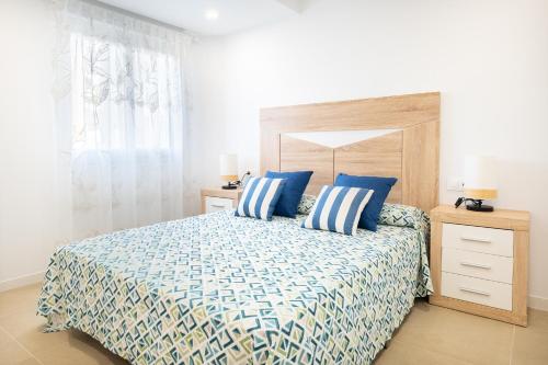 a bedroom with a bed with blue and white pillows at Global Properties, Bonito apartamento en Urbanizacion Ciudad Mar in Puerto de Sagunto