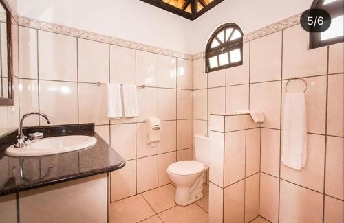La salle de bains blanche est pourvue de toilettes et d'un lavabo. dans l'établissement Pousada Caminho do Mar, à Imbassaí