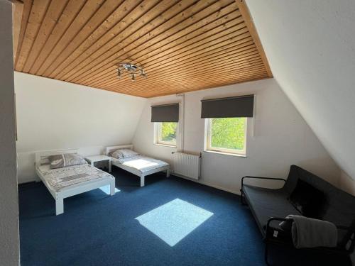 Cette chambre mansardée comprend un canapé, une table et 2 fenêtres. dans l'établissement Landhaus Huntlosen Monteure, à Großenkneten