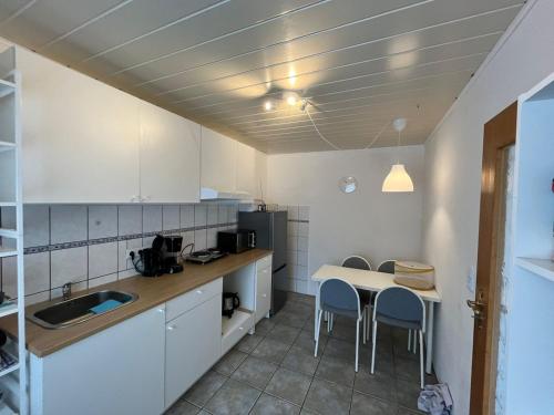 a kitchen with white cabinets and a table and chairs at Landhaus Huntlosen Monteure in Großenkneten