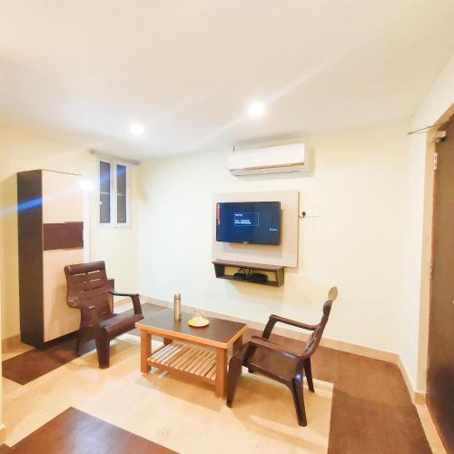 a living room with two chairs and a table and a tv at Srirathna Temple View Inn in Thanjāvūr