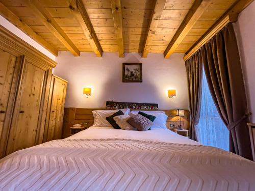 a bedroom with a large white bed with wooden ceilings at Hotel da Beppe Sello in Cortina dʼAmpezzo