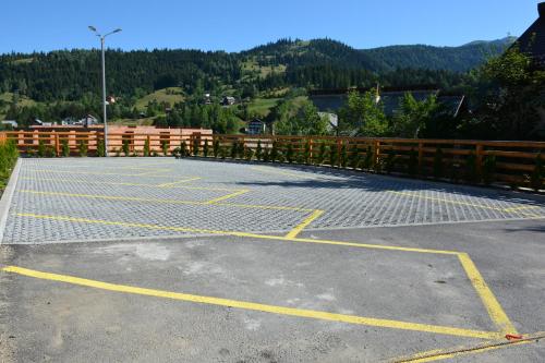 a parking lot with a fence and mountains in the background at PENSIUNEA DIANA SKI in Borşa