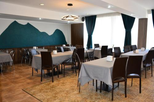 a dining room with white tables and chairs and a green wall at PENSIUNEA DIANA SKI in Borşa