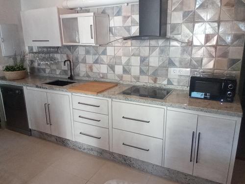 a kitchen with white cabinets and a tile wall at Alojamientos Biarritz VISTA JARDÍN in Fuenteheridos