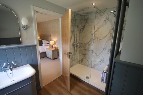 uma casa de banho com uma cabina de duche ao nível do chão e um lavatório. em The Horseshoe Country Inn em Pickering
