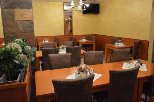 a dining room with tables and chairs and a television at Hotel Olga in Slavkov u Brna