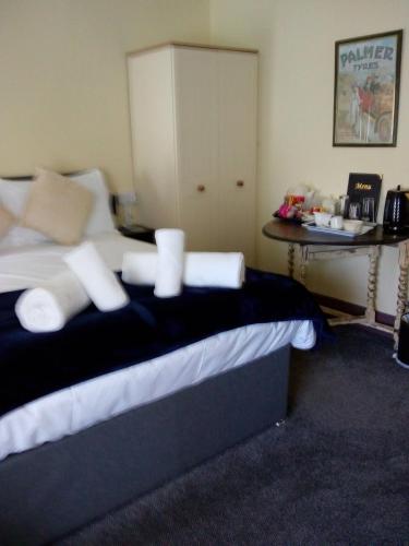a bedroom with a bed with white pillows and a table at THE KINGS ARMS INN in Stratton