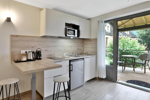 a kitchen with white cabinets and a table with stools at Domaine de La Rhonie in Meyrals