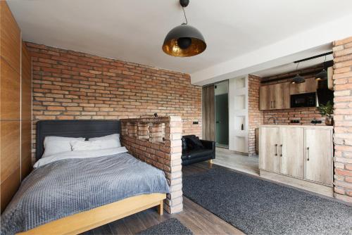 a brick walled bedroom with a bed and a kitchen at Industrial Studio in Budapest