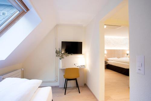 a bedroom with a bed and a yellow chair in a room at Kreuz Bern Modern City Hotel in Bern