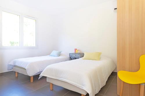 ル・ラヴァンドゥーにあるSELECT'SO HOME - Résidence La Fossette - Terrasse vue mer - Prestations de qualité & Services Hôteliers - FOS-04の黄色い椅子付きの客室内のベッド2台