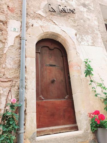 een grote houten deur in een stenen gebouw bij La Galine, Maison de village medieval in Lunas