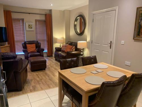 a living room with a wooden table and leather chairs at Sperrin View Apartment (Ground Floor) in Draperstown