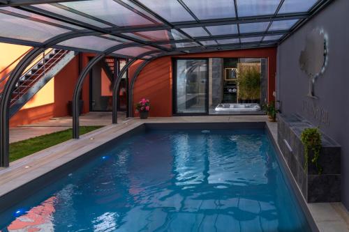 une piscine intérieure avec une pergola et une maison dans l'établissement Villa Seyal - avec piscine - jacuzzi - sauna & climatisation, au Mans