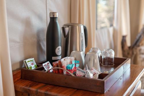 a wooden tray with a bottle on a table at Umkumbe Bush Lodge - Luxury Tented Camp in Sabi Sand Game Reserve