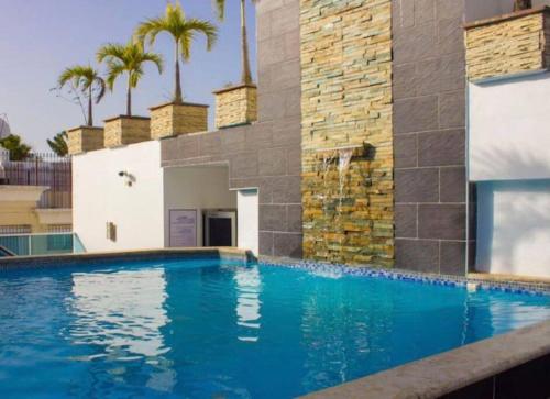 a swimming pool in front of a building with palm trees at New Condo Rooftop Pool. Gym. Discounted rate in Santo Domingo