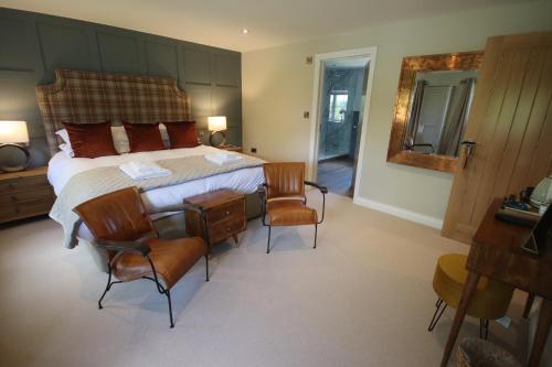 a bedroom with a large bed with chairs and a mirror at The Horseshoe Country Inn in Pickering