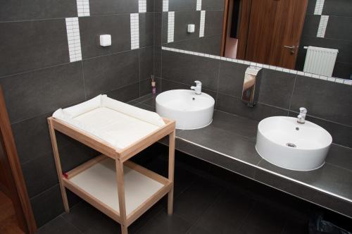 two white sinks in a bathroom with black tiles at Restaurace a penzion Zděná Bouda in Hradec Králové