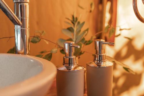 a bathroom with two soap dispensers next to a sink at Umkumbe Bush Lodge - Luxury Tented Camp in Sabi Sand Game Reserve
