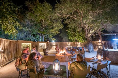 a group of people sitting around a fire pit at night at Umkumbe Bush Lodge - Luxury Tented Camp in Sabi Sand Game Reserve