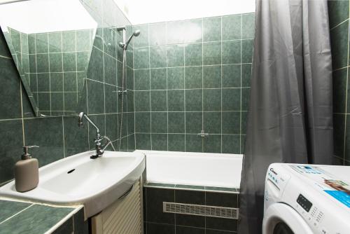 a green tiled bathroom with a sink and a shower at The Sunlight Studio in Budapest