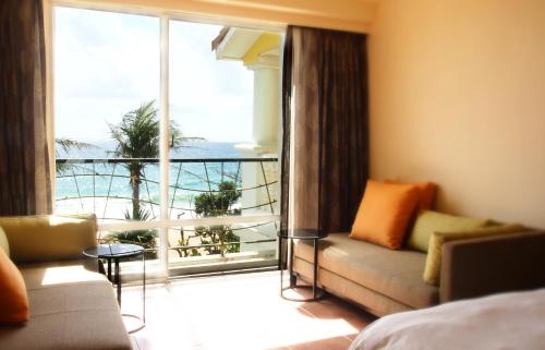 
a bedroom with a couch, chair and a window at Chateau Beach Resort Kenting in Kenting
