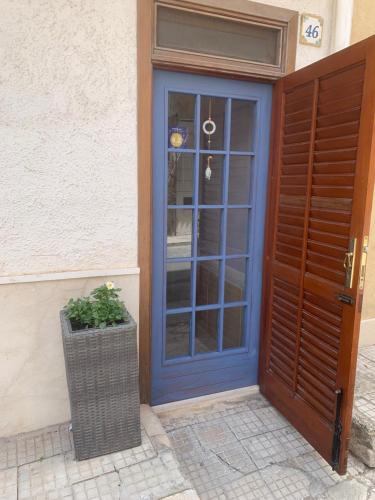 une porte bleue avec une plante en pot à côté d'un bâtiment dans l'établissement Alice's Apartment, à Castellammare del Golfo