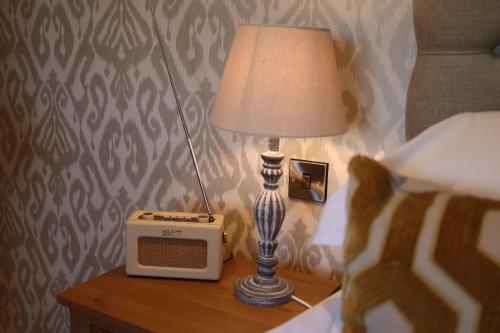 a lamp and a radio sitting on a table next to a bed at The Horseshoe Country Inn in Pickering