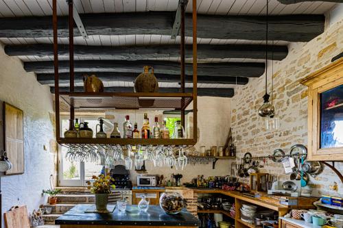 a kitchen with a table and a shelf with bottles at Le Domaine des Carriers in Chevroches