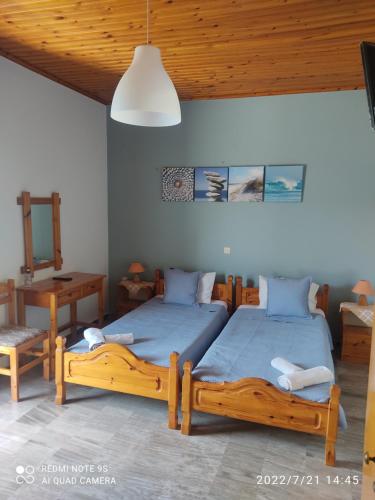 a bedroom with two beds and a table and a lamp at Studios Maro in Skala Kallonis
