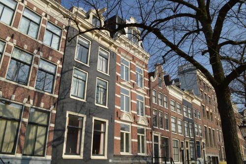 un grand bâtiment en briques avec un arbre devant dans l'établissement B&B Keizers Canal, à Amsterdam