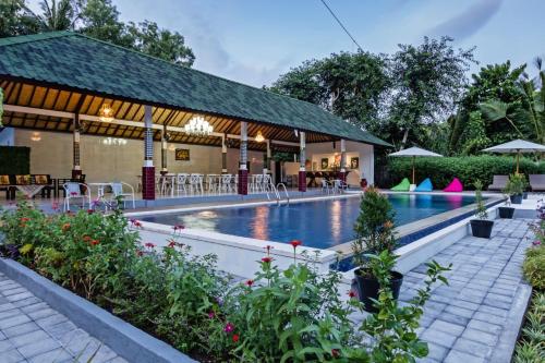 a swimming pool at a resort with tables and chairs at Kesari Penida by Mahaprana Home in Nusa Penida