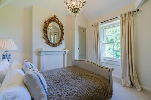 a bedroom with a bed with a mirror and a window at Peartree Cottage in Chippenham