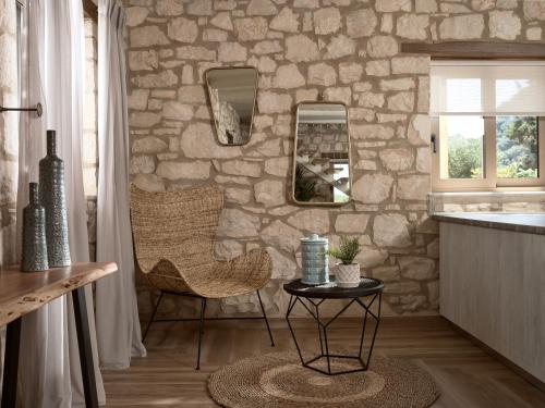 a kitchen with a stone wall with a chair and a table at Conte Nobile Villa, a Rejuvenating Retreat, By ThinkVilla in Vasilikos