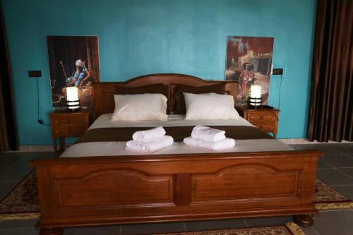 a bedroom with a large wooden bed with towels on it at Maison d'Hôte - Le Beau Panorama in Berkawe