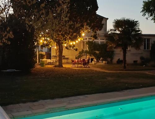 une maison avec un arbre et une table dans la cour dans l'établissement Le Magnolia, chambre d'hôte au calme, à Saumur