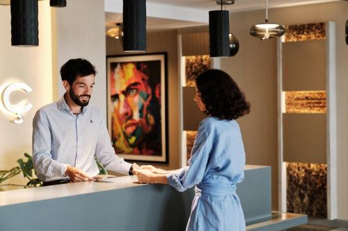 Un homme et une femme serrent la main à un comptoir dans l'établissement El Vicenç de la Mar - Adults Only - Over 12, à Cala Sant Vicenç