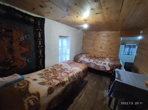 a bedroom with two beds in a room with wooden walls at Hotel Omalo2005 in Omalo