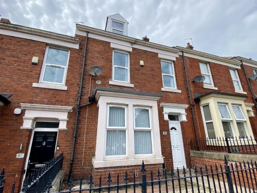 a red brick house with white windows and a fence at 89 St John's Road Terrace House in Newcastle upon Tyne