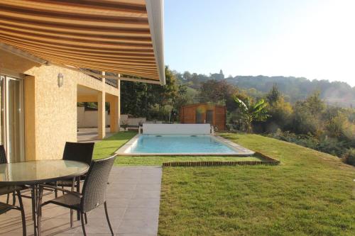 een patio met een tafel en stoelen en een zwembad bij Gite Les hauts du Lac in Carla-Bayle