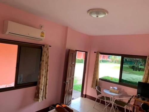 a living room with pink walls and a table and window at โพธิ์ทองริมทุ่ง Pothong Rimtung Hotel in Fang