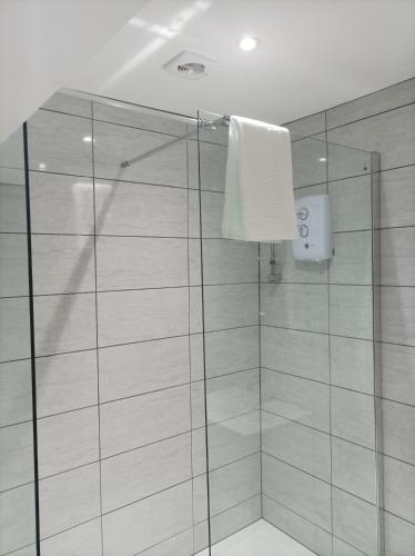 a shower with a glass door and a white towel at Rose James Apartments in Blackpool