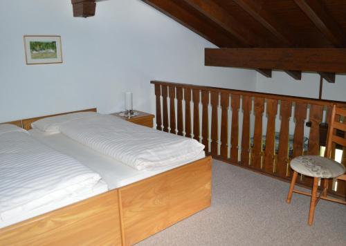 a bed with a wooden frame and a chair in a room at Residenz La Mora in La Punt-Chamues-ch