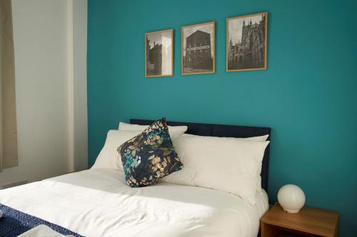 pared azul con cama con almohada en K Suites - Wellington Street 1 en Gloucester