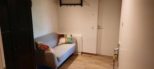 Cette petite chambre dispose d'un canapé bleu avec des oreillers. dans l'établissement Ferienwohnung Tuniberg, à Umkirch