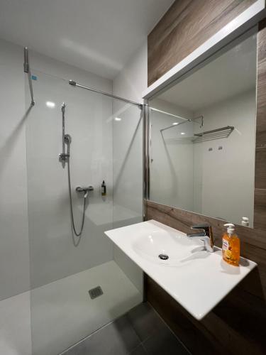 a bathroom with a white sink and a shower at Aparthotel Apartamenty Czarna Góra 112 in Sienna