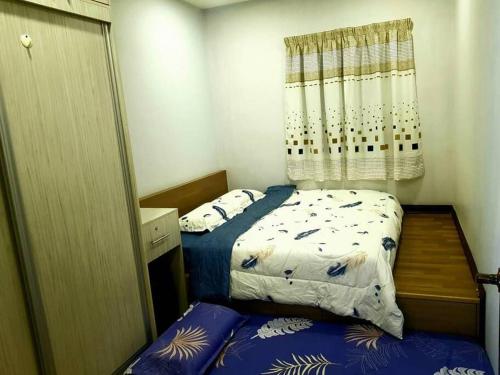 a small bedroom with two beds and a window at Best Sekinchan homestay in Sekinchan
