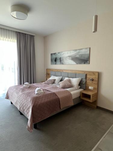 a bedroom with a bed and a large window at Aparthotel Apartamenty Czarna Góra 112 in Sienna