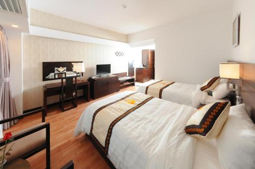a hotel room with two beds and a desk at Khách sạn Công Đoàn Quảng Bá in Hanoi